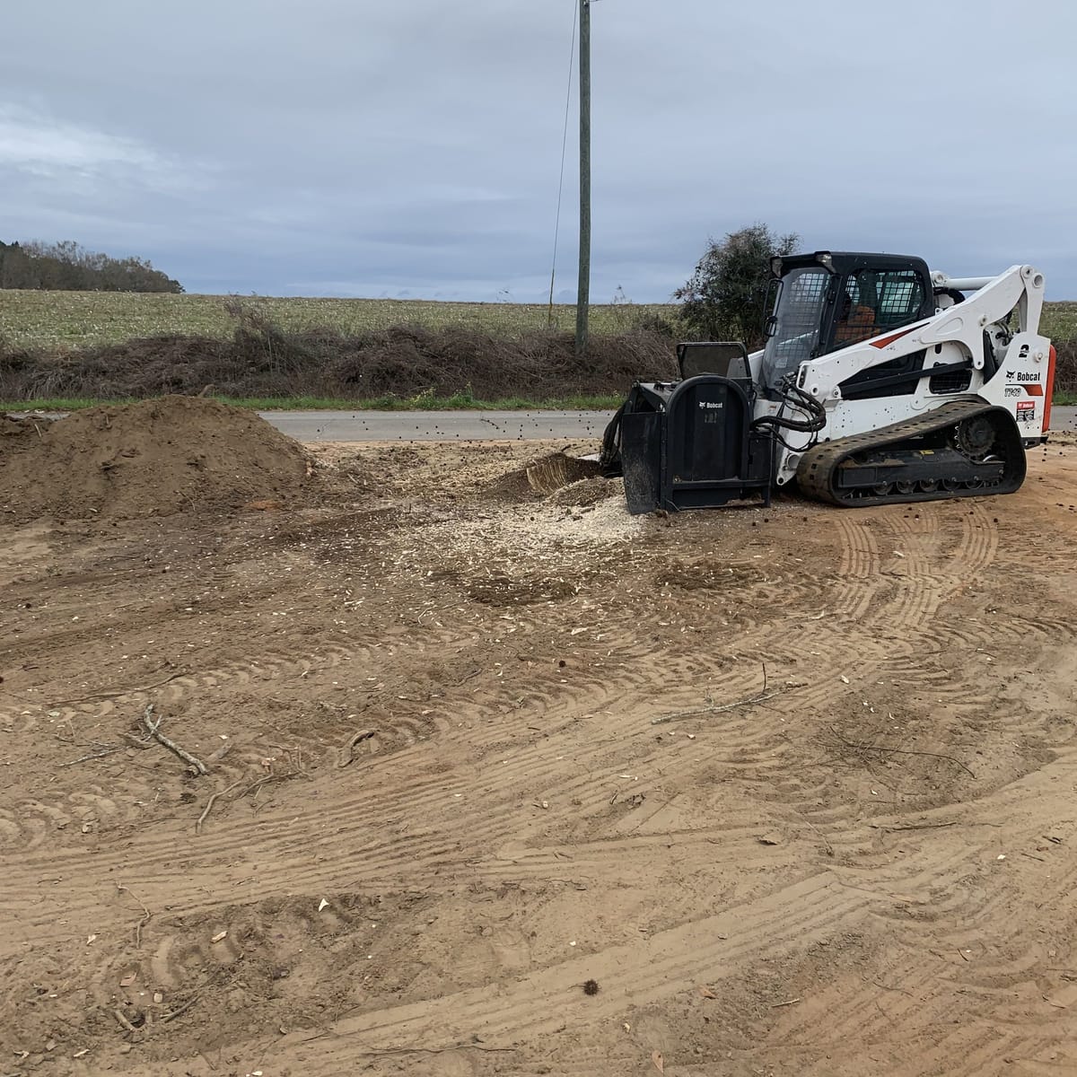 A skid steer grading the ground flat where a stump has been ground out